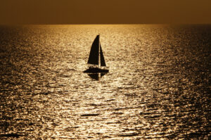 Sailboat gliding across golden evening water