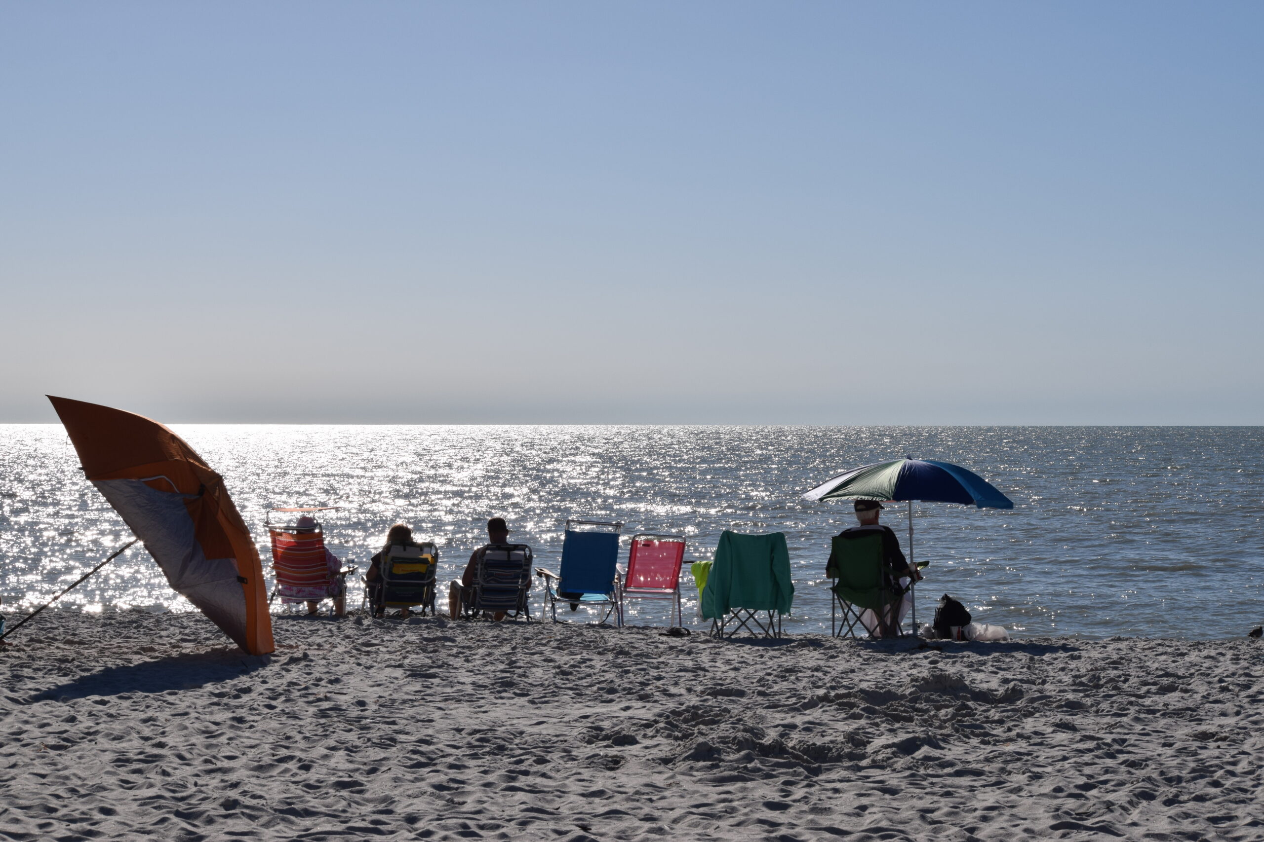 Beach chairs and umbrellas facing sparkling Gulf water on a sunny beach day, Marco Island, Florida