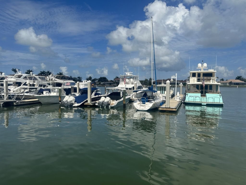 Boats docked in a sunny waterfront marina with condos behind them, Marco Island, Florida