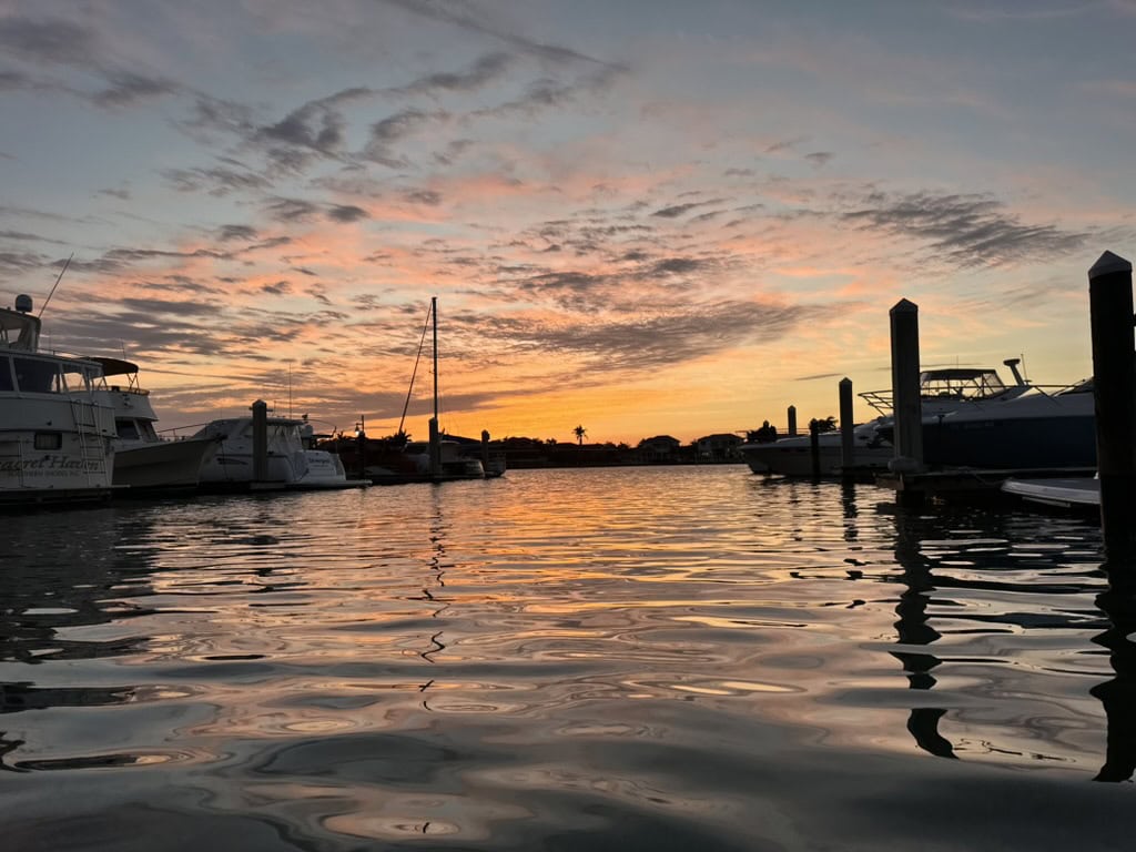 Marina docks and moored boats reflected in rippled water at dusk, Marco Island, Florida
