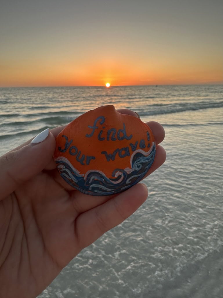 Hand holding a painted seashell with a beach message at sunset, Marco Island, Florida