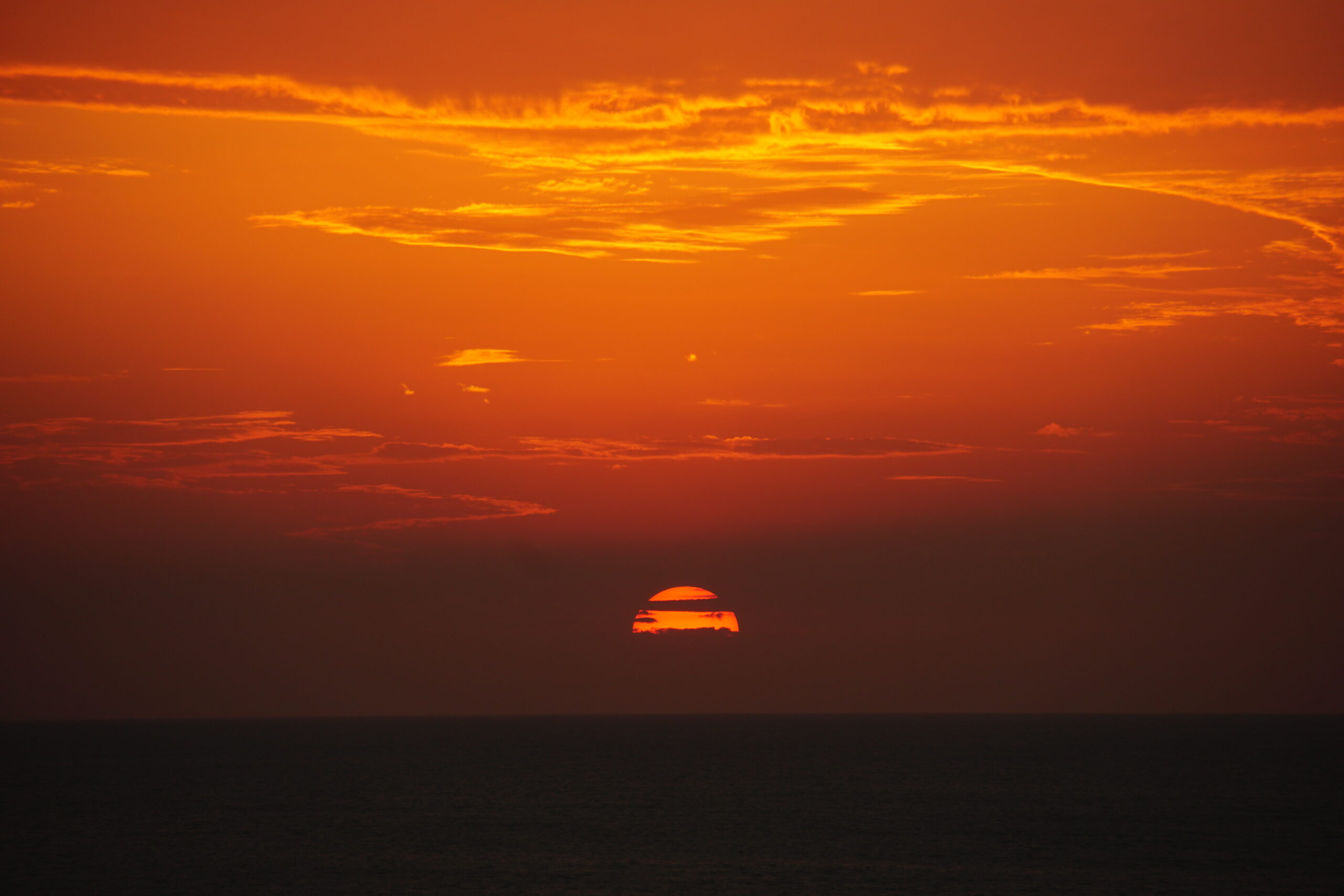 Deep orange sunset dropping through layered clouds over the Gulf of Mexico, Marco Island, Florida