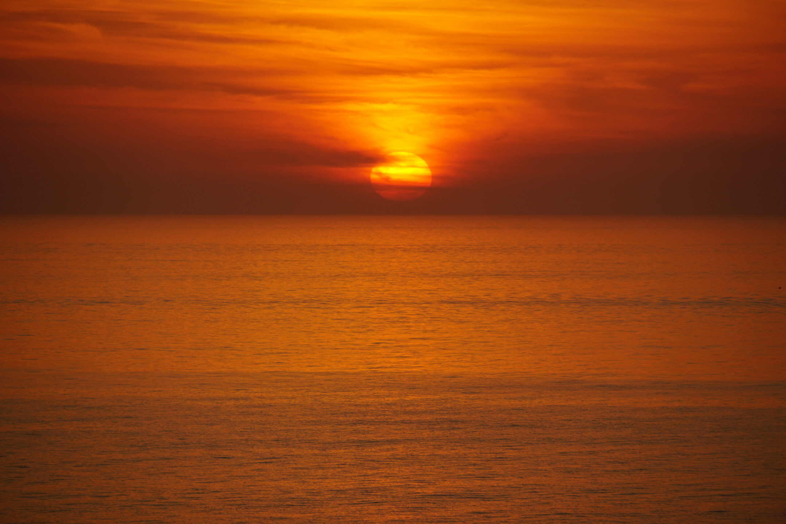 Fiery orange sunset reflecting across calm Gulf water on a hazy evening, Marco Island, Florida