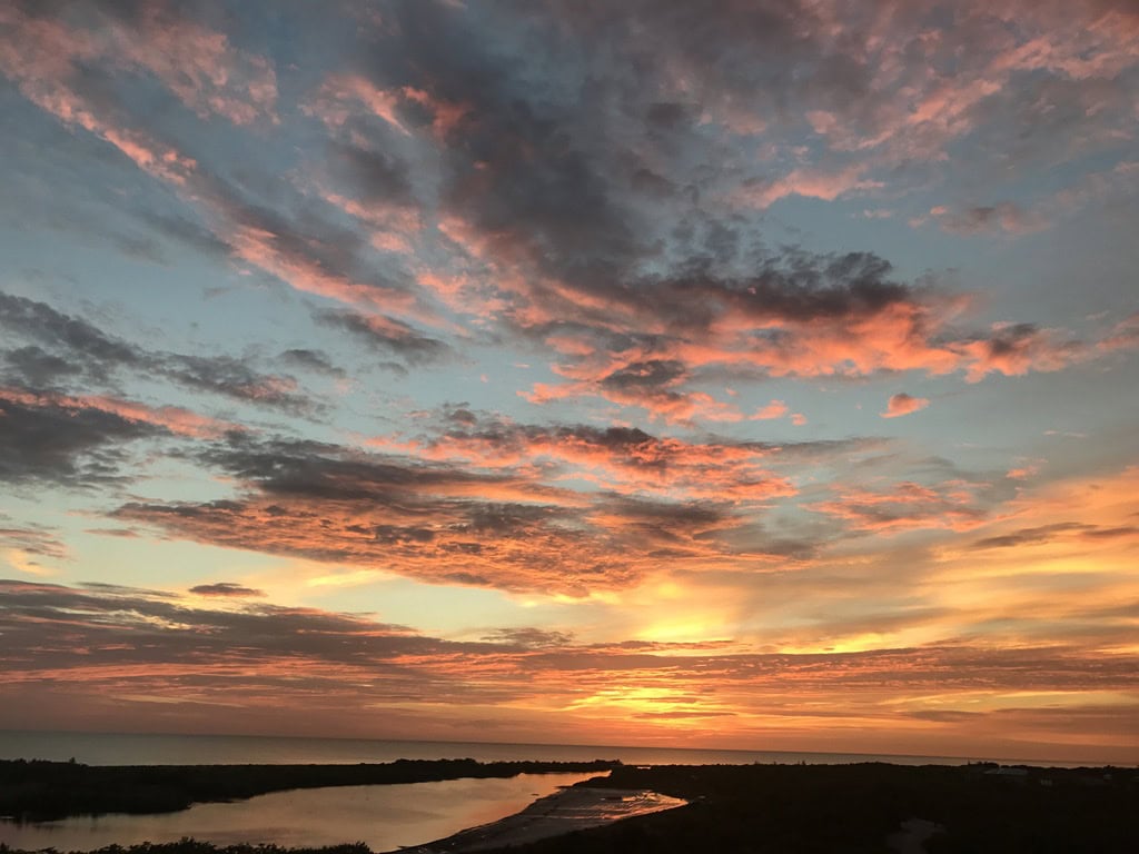 Vivid sunset clouds reflected over a quiet lagoon and dark shoreline, Marco Island, Florida