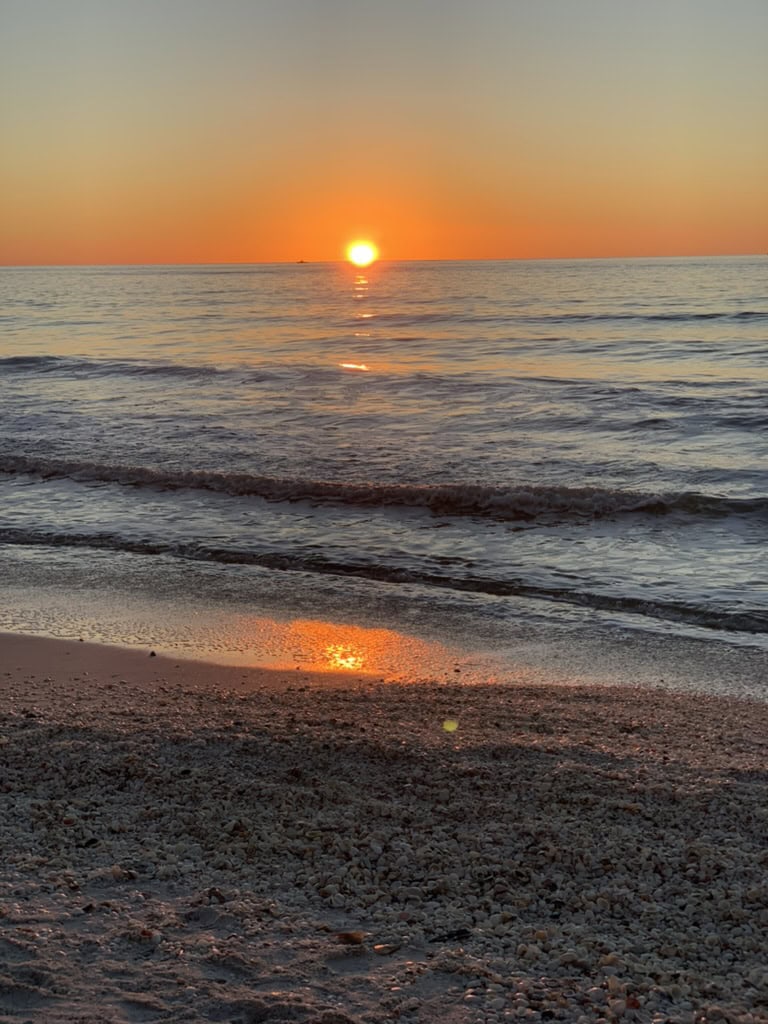 Golden sunset reflecting on gentle Gulf surf and wet beach sand, Marco Island, Florida