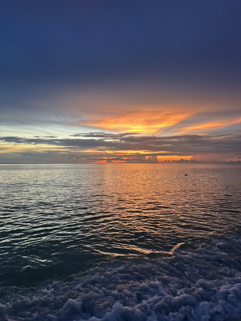 Orange sunset glowing over the Gulf behind a foamy boat wake from a moving boat, Marco Island, Florida
